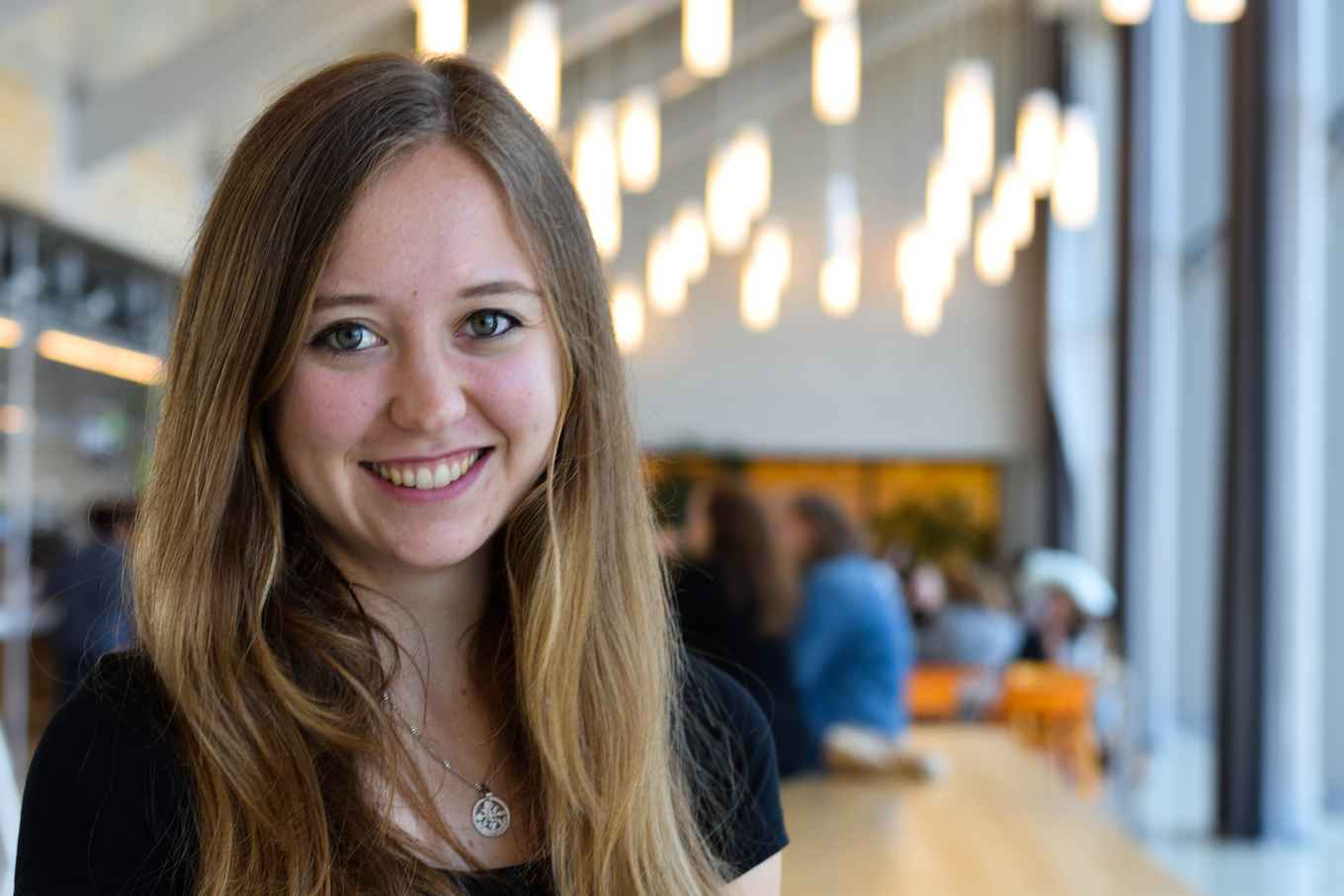 Student smiling at camera, lights in the back